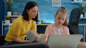 Mother and daughter learning together with books and laptop
