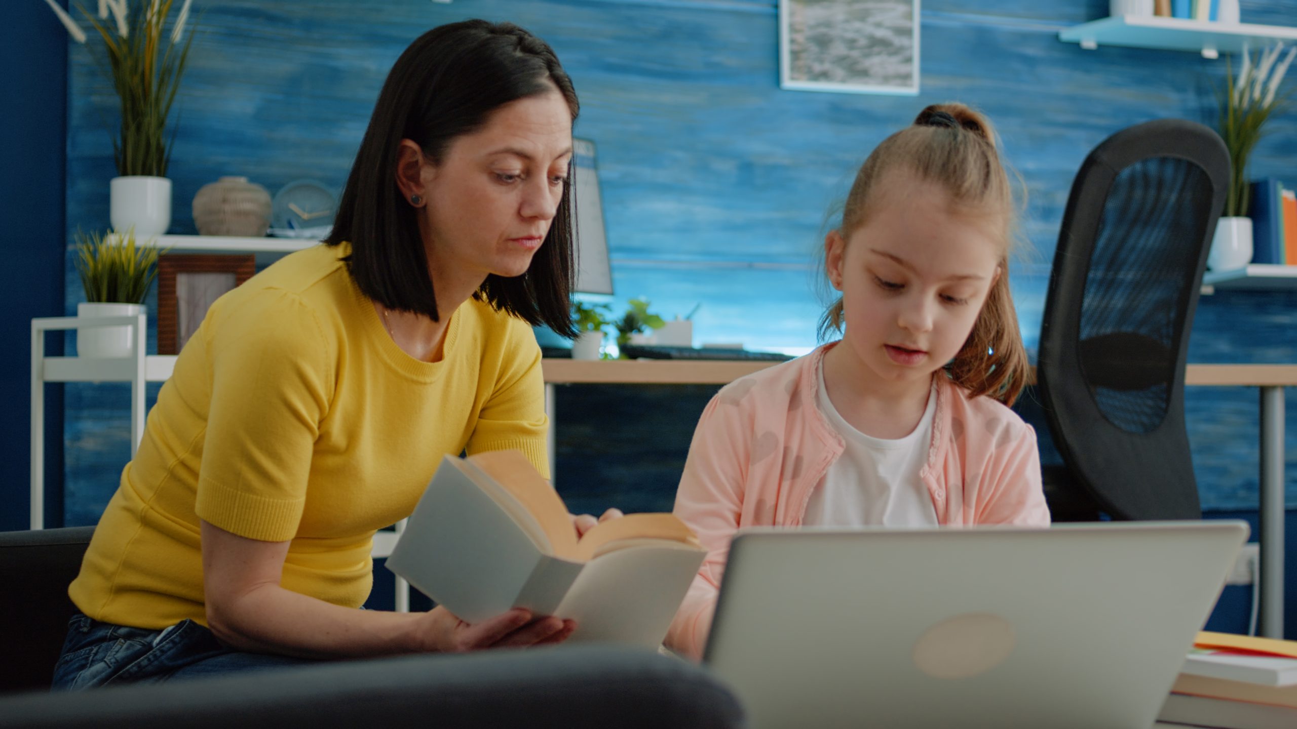 Mother and daughter learning together with books and laptop